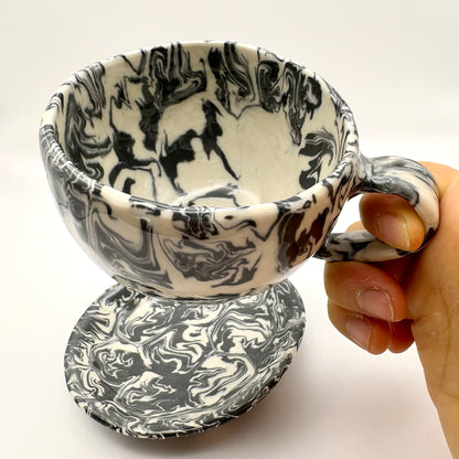 Handmade Ink Storm Nerikomi porcelain mug and saucer set featuring high-contrast black and white marbled patterns and a glossy clear glaze, 6oz capacity.