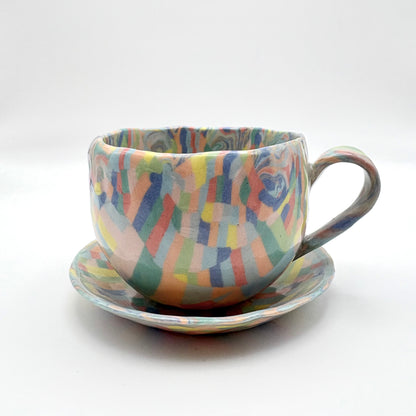 Handmade Rainbow Nerikomi porcelain mug and saucer set with vibrant multi-colored marbled patterns and a glossy clear glaze, 6-8 oz capacity.