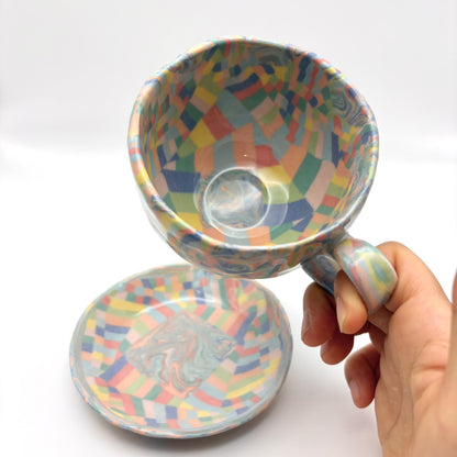 Handmade Rainbow Nerikomi porcelain mug and saucer set with vibrant multi-colored marbled patterns and a glossy clear glaze, 6-8 oz capacity.