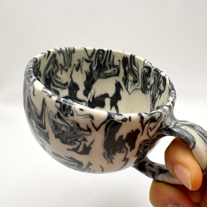 Handmade Ink Storm Nerikomi porcelain mug featuring high-contrast black and white marbled patterns and a glossy clear glaze, 6oz capacity.