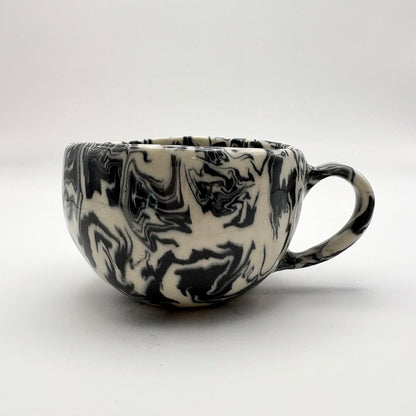 Handmade Ink Storm Nerikomi porcelain mug featuring high-contrast black and white marbled patterns and a glossy clear glaze, 6oz capacity.