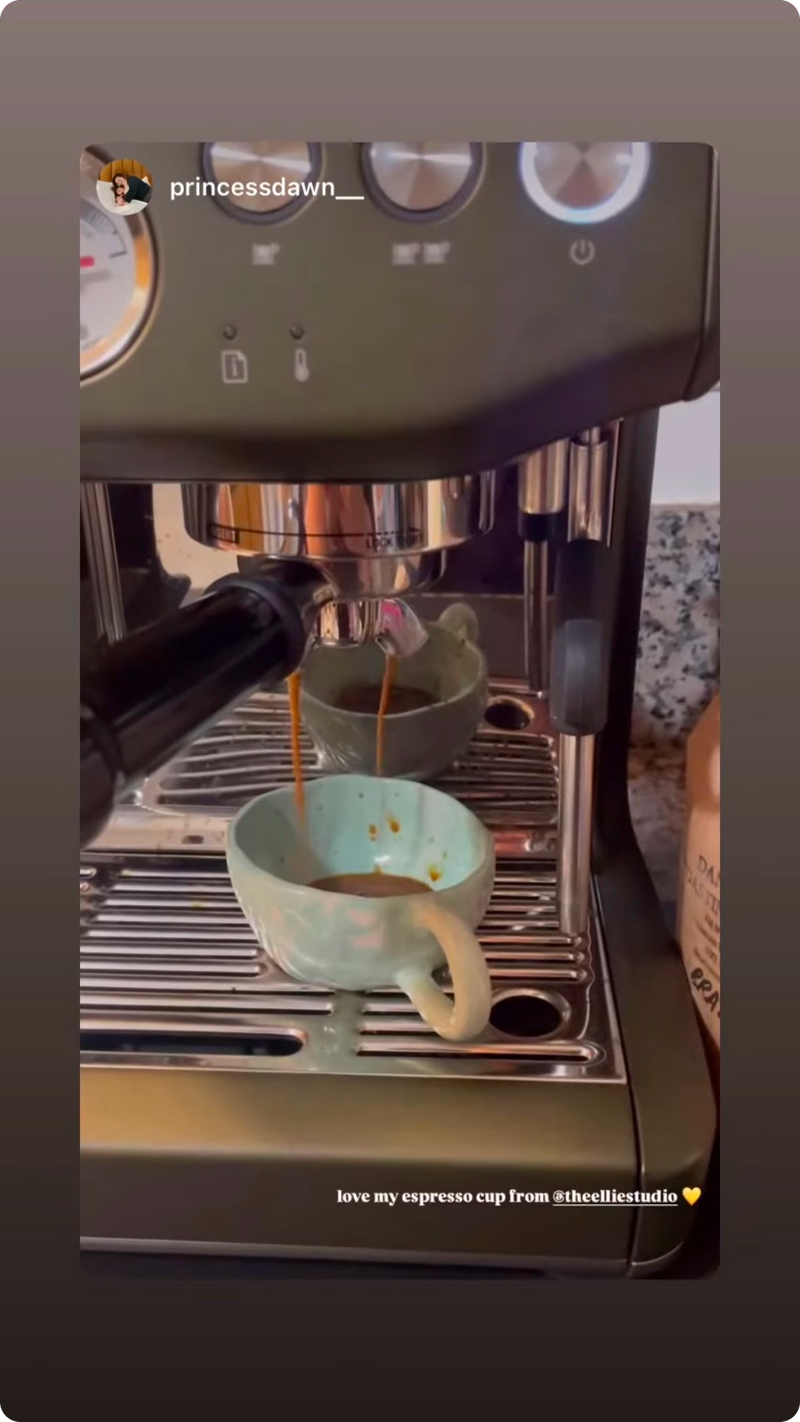 Pastel green and white marbled nerikomi espresso mug being used with coffee dripping from the espresso machine to the mug