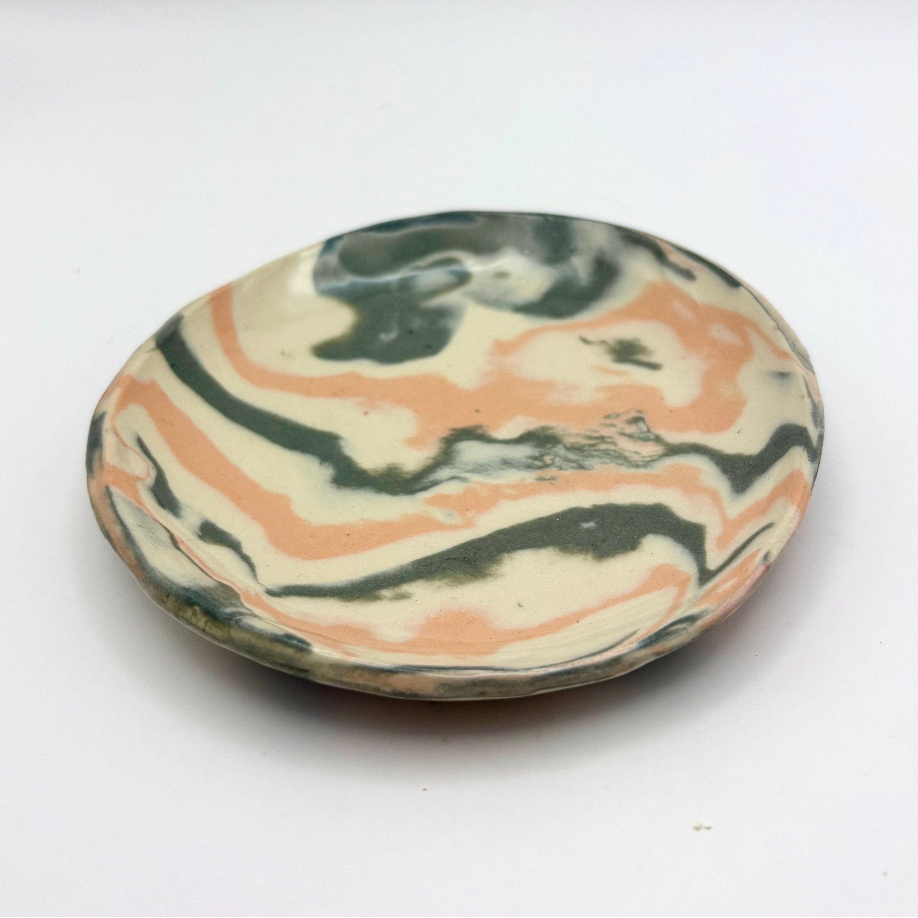 Handmade patterned ceramic plates created by students in a Nerikomi workshop. Black white and orange marbled plate saucer