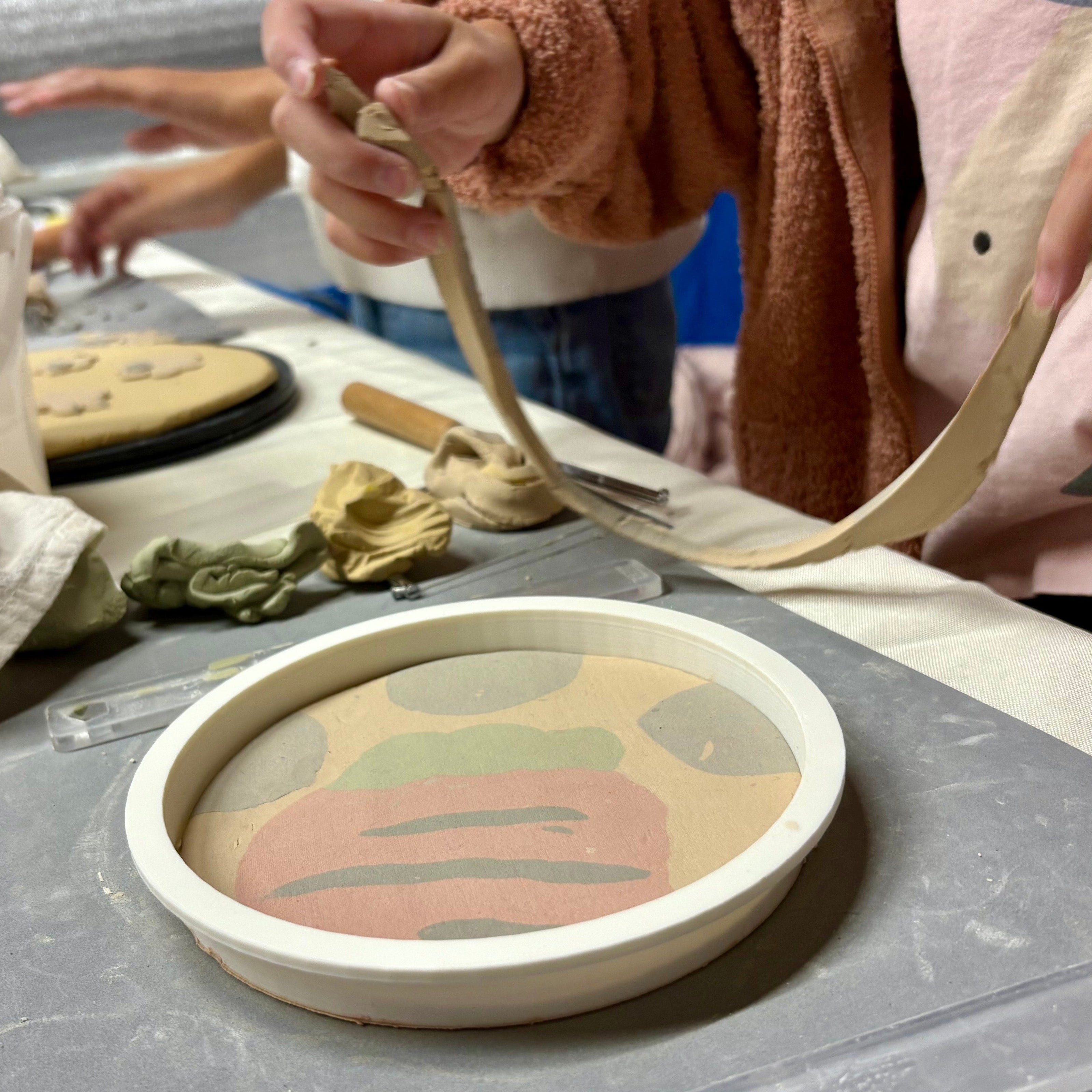 Person working on a ceramic piece with carrot design