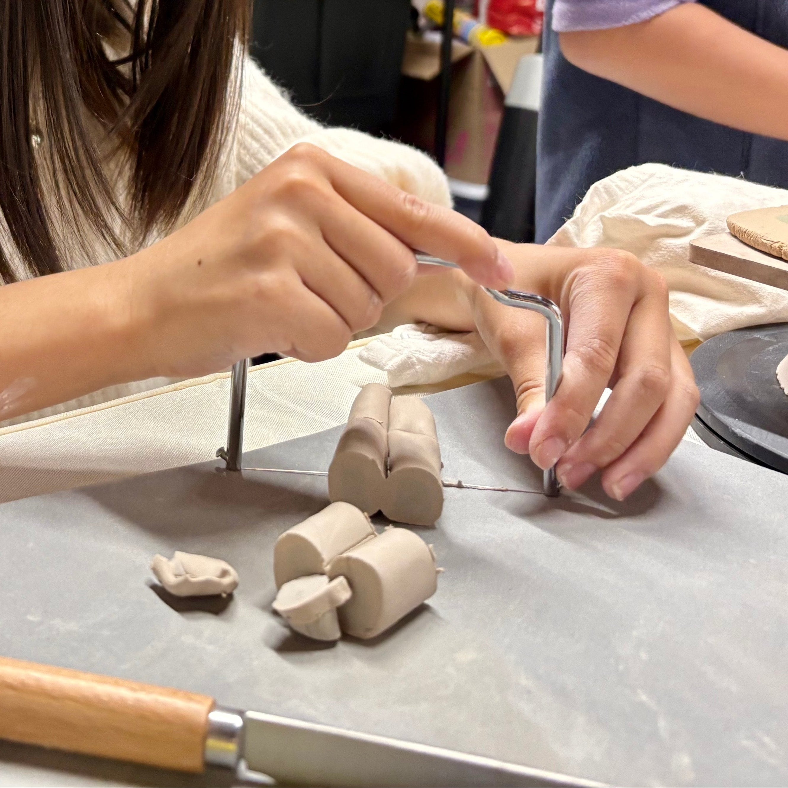 Person working with clay on a table with tools